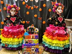 two people dressed in colorful costumes standing next to each other with decorations on the wall behind them