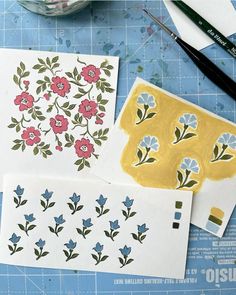 some flowers are painted on paper with paintbrushes