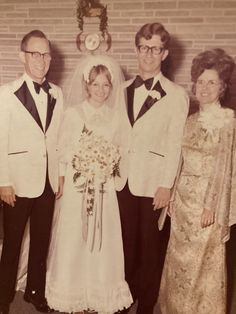 an old black and white photo of a bride and groom with their parents in front of a brick wall