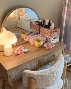 a vanity with a mirror, lamp and various items on it in front of a bed