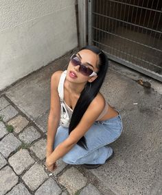 a woman sitting on the ground wearing sunglasses