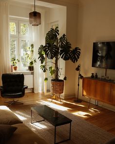 a living room filled with furniture and a flat screen tv mounted on the wall next to a window