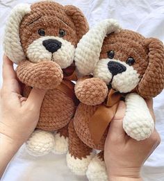 two brown and white stuffed animals being held by someone