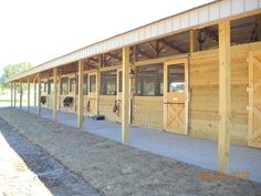 the inside of a horse barn with wooden stalls