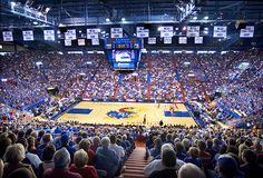 an indoor basketball game is being played in a stadium full of people and fans watching