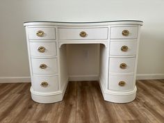 a white desk with gold handles and drawers