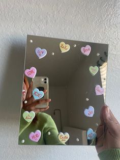 a person holding up a mirror with hearts on it and the reflection of someone taking a selfie