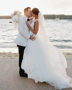 a bride and groom kissing on the beach