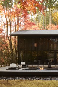 a house in the woods surrounded by trees with autumn foliage around it and an open fire pit