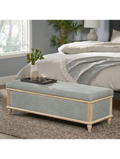 a bed with a gray blanket on top of it and a wooden bench in front of the bed