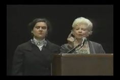 two women standing behind a podium talking on the phone