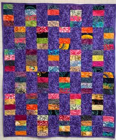 a purple quilt with many different colored squares on the front and back, all made up of