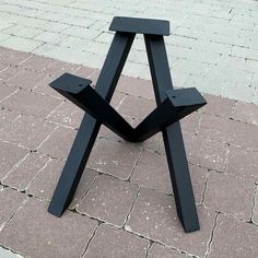 a black wooden table sitting on top of a brick walkway next to a sidewalk with cobblestone