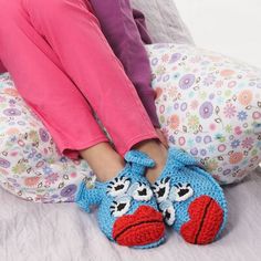 a child's feet in crocheted slippers sitting on a bed