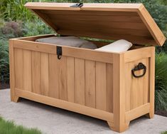 a large wooden storage box sitting on top of a cement ground next to some grass