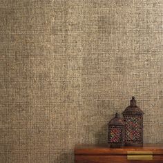 a wooden table with a lamp on top of it next to a brown wallpaper