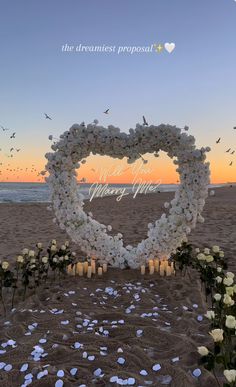 a heart shaped flower arrangement on the beach