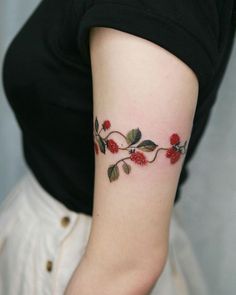 a woman's arm with red flowers and leaves tattooed on the left side of her arm