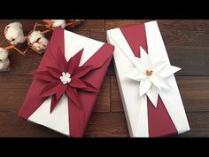 two wrapped presents sitting on top of a wooden table next to cotton flowers and twine