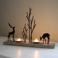 three candles are lit in front of some deer figurines