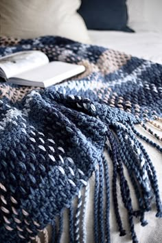 a blue and white blanket sitting on top of a bed next to a laptop computer