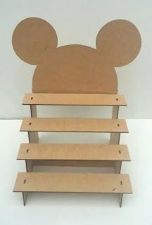 a cardboard mickey mouse head sitting on top of a wooden book shelf with three shelves below it