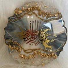 a decorative glass plate with arabic writing and gold trimmings on the edge, sitting on a white furnishing