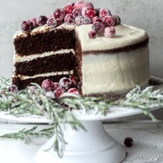 a cake with frosting and cranberries sitting on top of a white plate