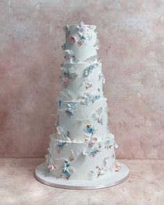 a three tiered white wedding cake with blue and pink flowers on the bottom layer