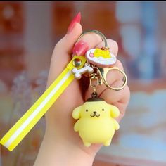 a hand holding a yellow keychain with a cartoon character on it and a cute little dog charm attached to it