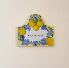 a yellow and blue ceramic plaque with the words your number written in white lettering on it