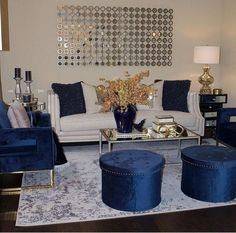 a living room filled with blue velvet furniture and gold accents on the wall above it