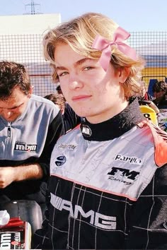 a young man with a pink bow on his head looking at a cell phone in front of him