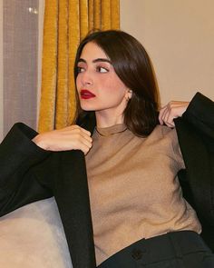 a woman sitting on top of a couch wearing a brown shirt and black blazer