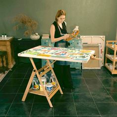 a woman is painting on an easel in a room with black tile flooring