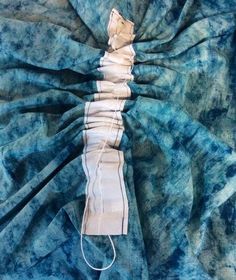 a piece of blue and white dyed material on top of a bed sheet with an electrical cord attached to it