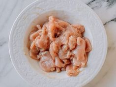 a white bowl filled with food on top of a marble countertop next to a knife and fork