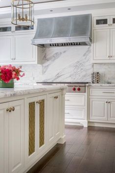 a large kitchen with white cabinets and marble counter tops, along with an island in the middle