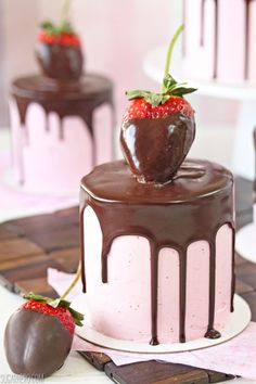 chocolate covered cake with strawberry on top and two other cakes in the back ground,