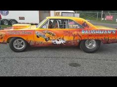 an orange and black car with flames painted on it's side in a parking lot