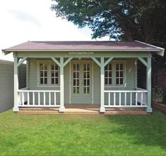 a small gray and white shed sitting on top of a lush green field