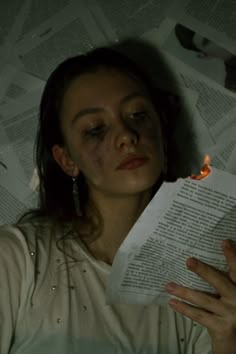 a woman is reading a book in the dark with her eyes closed and lit by a candle