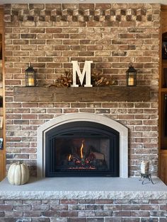 a brick fireplace with the letter m on it's mantle and two pumpkins