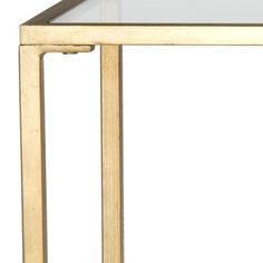 a glass top table with metal legs and gold trimmings on the bottom, against a white background