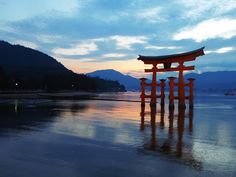 an orange gate stands out in the water at dusk, with mountains in the background