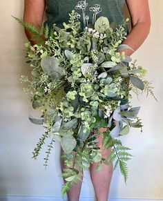 a man holding a bouquet of greenery in his hands