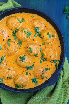 a pan filled with meatballs and sauce on top of a green towel