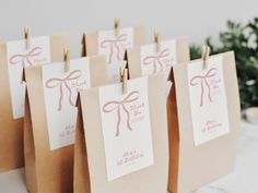 small brown bags with pink bows tied to them on a white tablecloth covered table