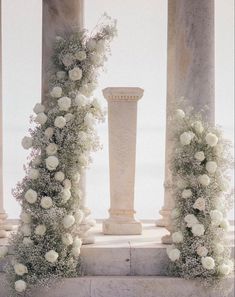 white flowers and greenery are on the pillars