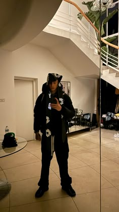 a man standing in front of a spiral staircase looking at his cell phone while wearing a hoodie